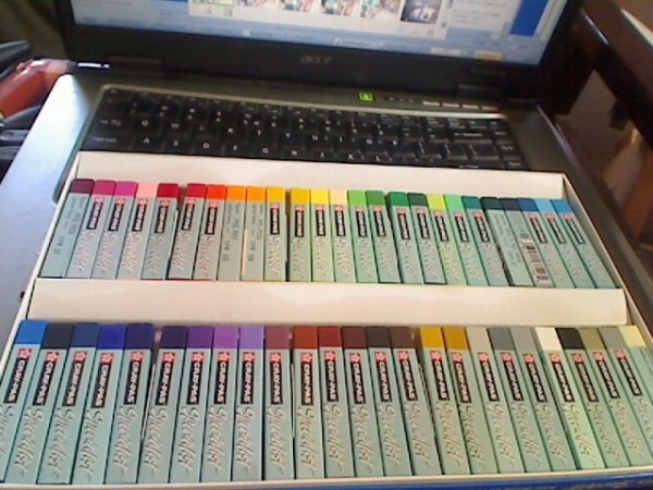 Photo of 50 color set of CrayPas Specialist artist grade oil pastels on laptop keyboard.